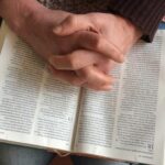 biddende handen op bijbel